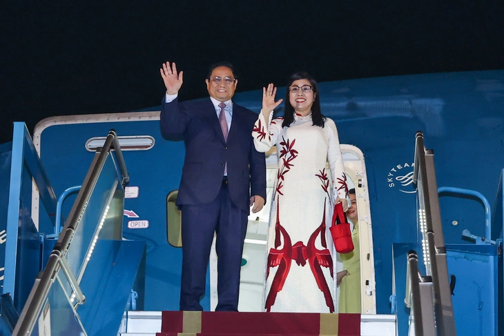 Thủ tướng Phạm Minh Chính và phu nhân vẫy tay chào trước khi vào chuyên cơ, lên đường đến châu Âu rạng sáng 16-1 - Ảnh: NHẬT BẮC