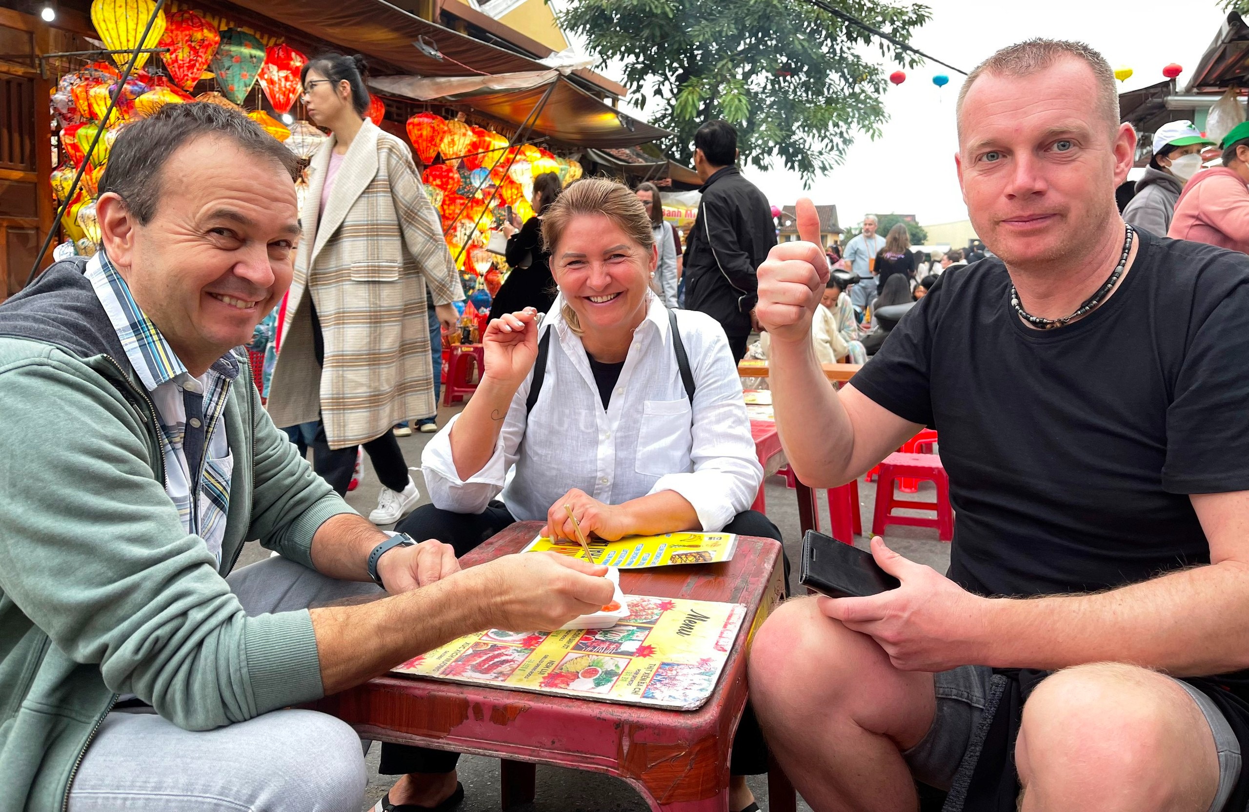 Du khách nước ngoài vui vẻ thưởng thức ẩm thực trong phố cổ Hội An, tháng 2.2024 - ảnh: Bảo Duy
