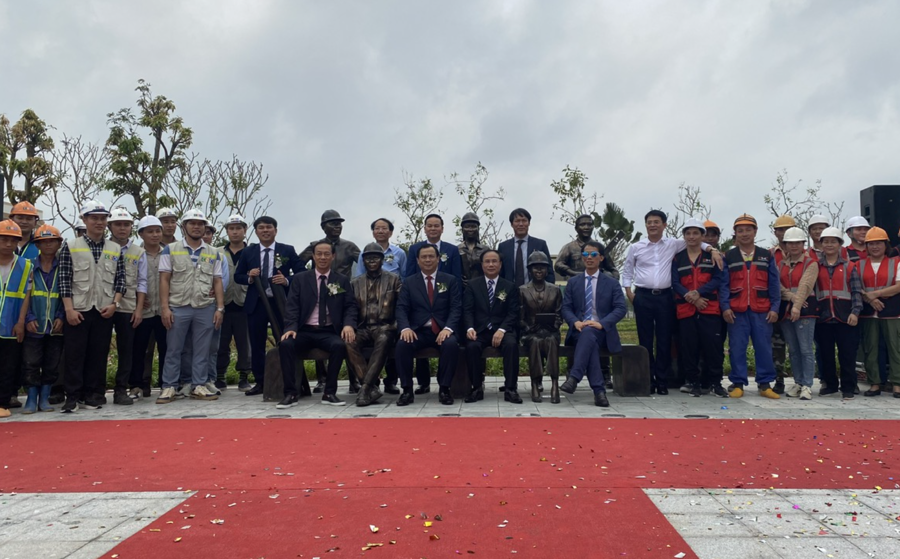 Các đại biểu chụp ảnh lưu niệm cùng Biểu tượng vinh danh Người xây dựng trong khuôn viên vườn hoa ở Quảng Ninh